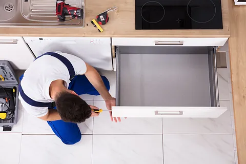 hombre reparando mueble de cocina